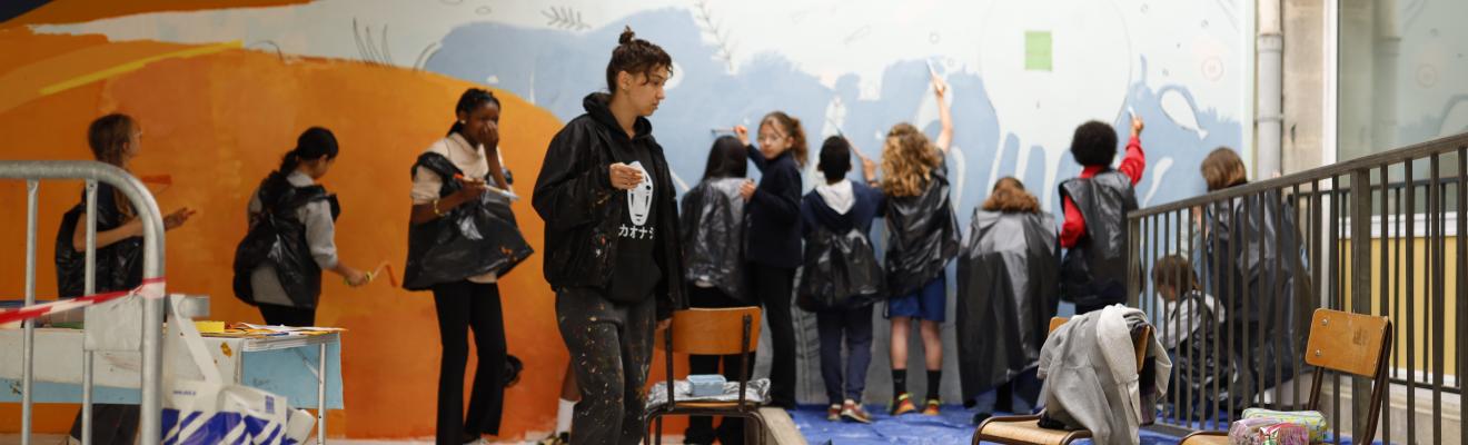 l'artiste et les enfants lors de la peinture de la fresque dans la cours de l'école Vieux Bordeaux