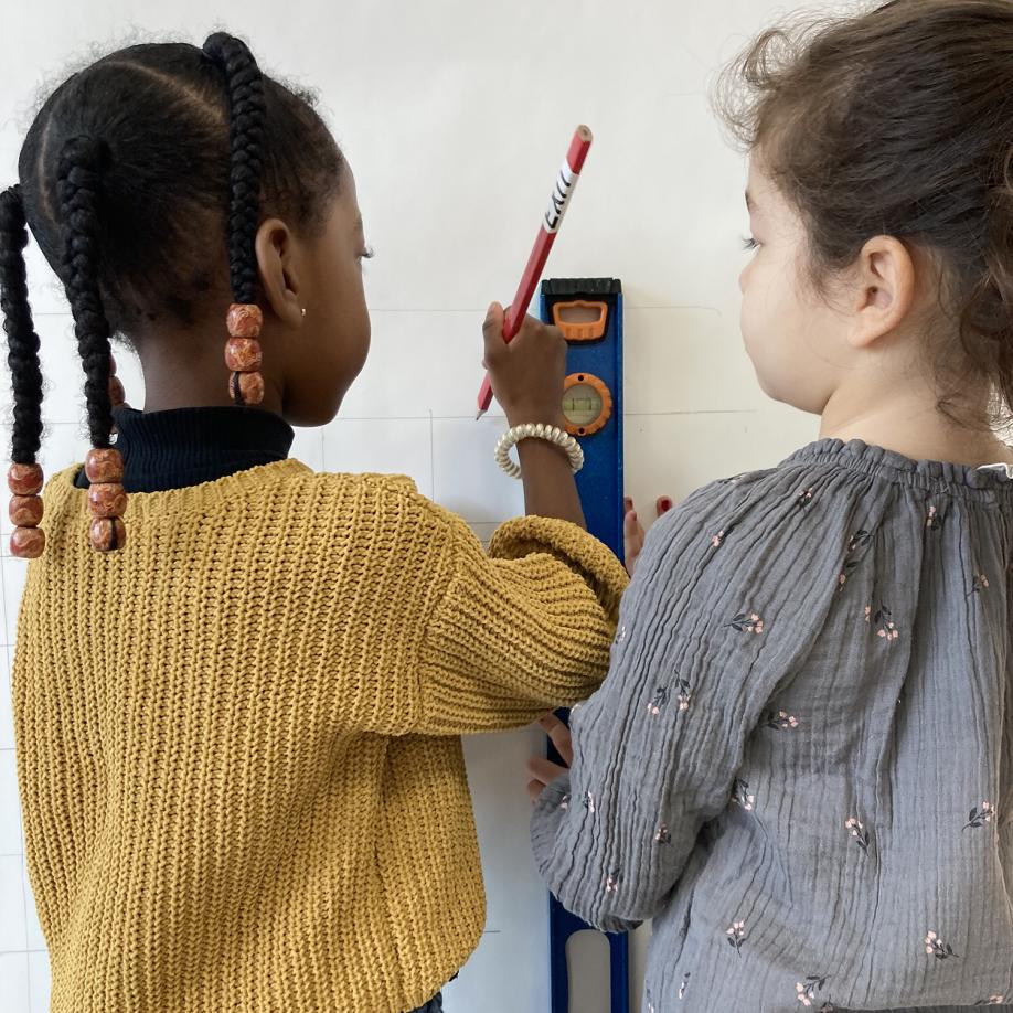 élèves de maternelle familiarisent avec le niveaux pour tracer une grille sur le mur.